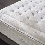 Photo présentant un zoom sur un matelas de haute qualité blanc, ainsi des motifs de fleur et de formes géométrique.